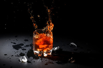 Glass of whiskey with ice on black background