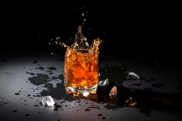 Glass of whiskey with ice on black background