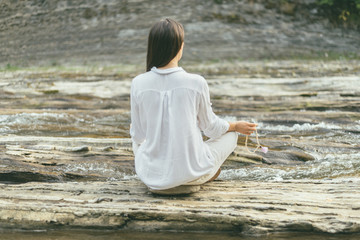 peaceful woman is making mantra meditation near river