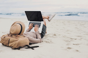 Young woman using laptop computer on a beach. Freelance work, distance learning, vacation concept
