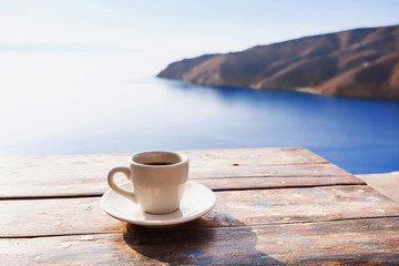 Cup of coffee on a table over blue sky and sea. Summer holiday concept