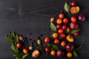 Picture of fruit isolated over dark wooden background, blueberries, alich, plums on black table,...