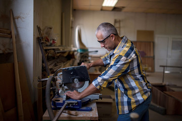 The carpenter uses a wood-cutting machine