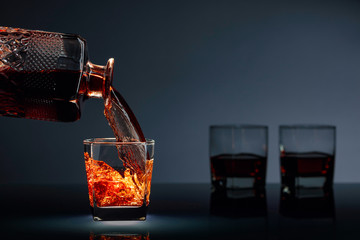 Alcoholic drink pouring from a decanter into a glass.