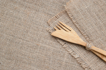 Set of wooden bamboo cutlery: fork, knife and spoon on sackcloth background with copy space. Top...