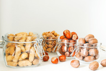 Various nuts selection: hazelnuts, pistachio and pecans in glass,space for copy or text,selective focus