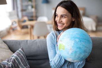 Portrait of a beautiful happy woman with a globe indoors.