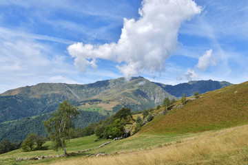 Paesaggio alpino, con il cielo blu e le nuvole bianche.