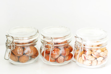 Various nuts selection: hazelnuts, pistachio and pecans in glass jars,space for your text