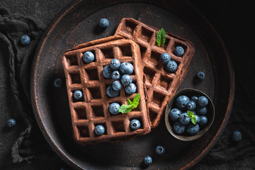 Waffles made of cocoa with berry fruits on dark table