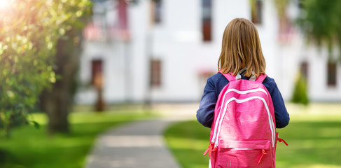 Girl with rucksack infront of a school building