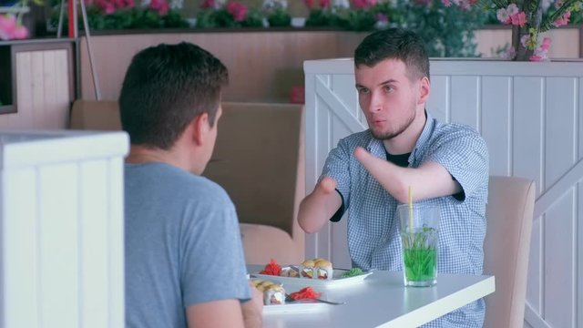 Problem of adaptation to usual life guy without wrists. Disabled man with two amputated stump hands meets friend and talks having lunch in cafe. Friend support communication. Person with disabilities.