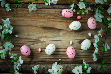 branch of spring flowers and colorful pink candy eggs for easter on rustic background