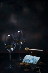 White wine in fine glass with blue cheese,honey,walnuts on dark background