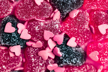 Beautiful marmalade hearts with powdered sugar, small pink and red heart candies, Valentine's day background