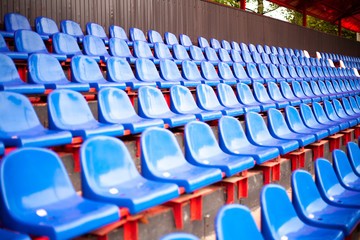 Rows of seats in the stadium. Blue seats in the sports arena. A place to watch sports.
