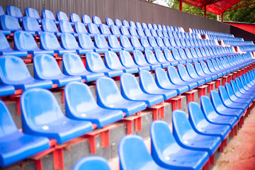 Rows of seats in the stadium. Blue seats in the sports arena. A place to watch sports.