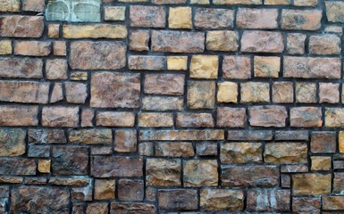 Solid brick and stone wall with different colors and shapes. Some stains are also present from wear...