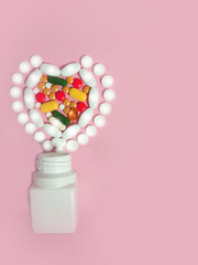 The pills are laid out in the shape of a heart near the bottle. On a pink background. Top view. Space for text.