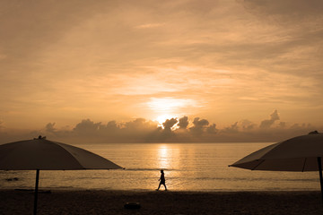 Fototapeta na wymiar Sunset on the sea. Silhouette of people walking in sunshine along the beach at sunset.