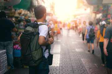 Back side of Young Asian traveling men walking and looking in china town walking street in evening at Bangkok, Thailand, traveler and tourist concept