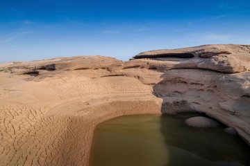 Fototapeta premium view of Nature rock and water in Mekong river with blue sky background, Sam Phan Bok known as The Grand Canyon of Thailand, attraction in Ubon Ratchathani, Thailand.