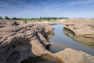 Fototapeta na wymiar view of Nature rock and water in Mekong river with blue sky background, Sam Phan Bok known as The Grand Canyon of Thailand, attraction in Ubon Ratchathani, Thailand.