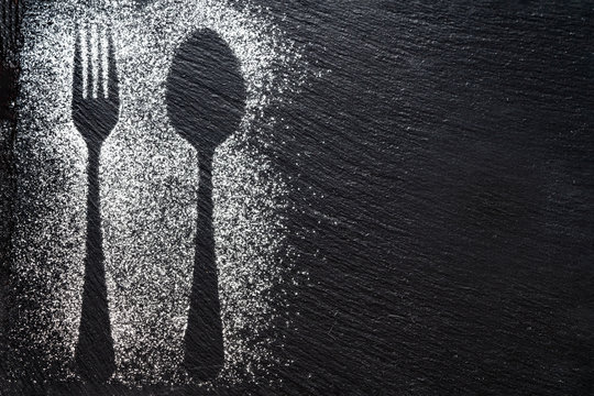 Spoon and fork silhouette made with flour on dark texture background, up horizontal view