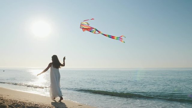 Teen girl runs with a kite along the seashore
