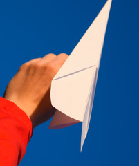 White paper airplane in hand against the sky. A symbol of freedom on the Internet