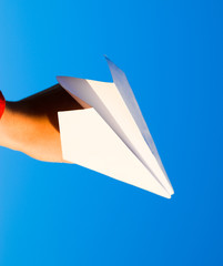 White paper airplane in hand against the sky. A symbol of freedom on the Internet