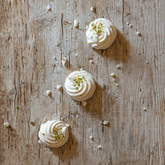 White marshmallows on old wooden background decorated with pistachios. Top view