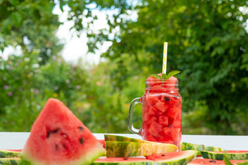 Summer Watermelon drink in glass and slices of watermelon outdoors