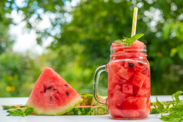 Summer Watermelon drink in glass and slices of watermelon outdoors