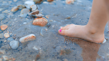Pies de bebé en el agua con tierra y piedras