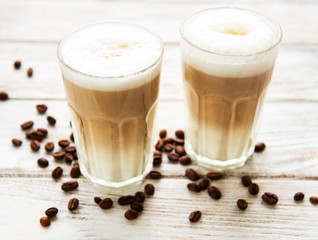 Two glasses of latte coffee and coffee beans