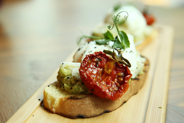 Poached egg on toast with avocado. An appetizing breakfast is served on a wooden board. Close-up.