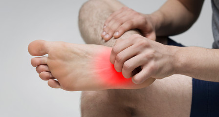 Man scratching bare foot with red rush