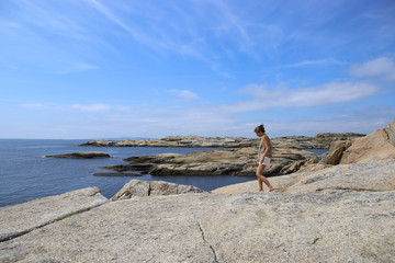 Fototapeta na wymiar Woman admiring magestic view of islets and rocks in The End of the Earth in Norway. Verdens Ende (World's End) is composed of various islets and rocks and is a popular recreational area with fantasti
