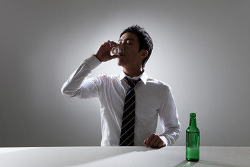 Image of a businessman drinking alcohol by himself.