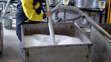 Production plant worker Works with loader Hose vacuum sucking white virgin plastic granules from tank in factory workshop