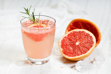 Glass of grapefruit drink with ice and rosemary