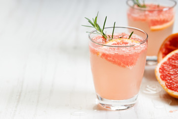 Glass of grapefruit drink with ice and rosemary