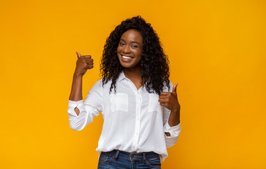 Happy black woman showing thumbs up at studio