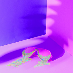 Iridescent shimmering liquid dripping from colored fashionable sunglasses in ultraviolet.
