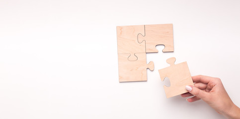 Woman creating wooden puzzle of four pieces with copy space