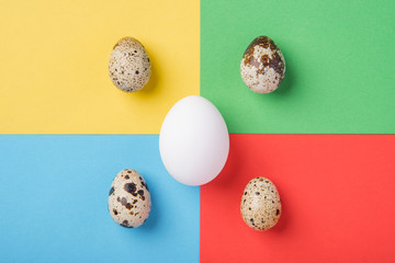 Beautiful spotted fresh quail and chicken eggs on a green, blue, yellow and red background