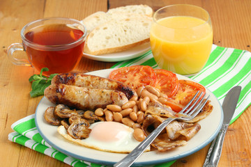 Classic English breakfast served: eggs, bacon, beans, juice and tea	v