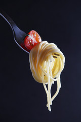 Cooked spaghetti on a fork with a tomato cherry