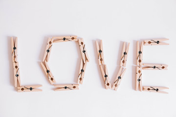 Wooden clothespins on a white background with the inscription the word love. View from above